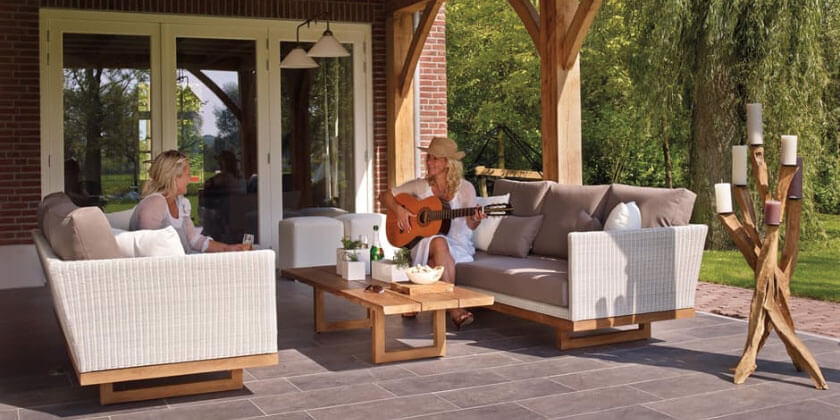 Two individuals enjoying leisure time on an outdoor patio in Boston, one playing guitar and the other listening.