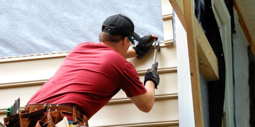 Worker, serving as a general contractor, caulking around a window frame.