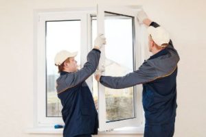 Two contractors from a Boston construction company installing a new window.